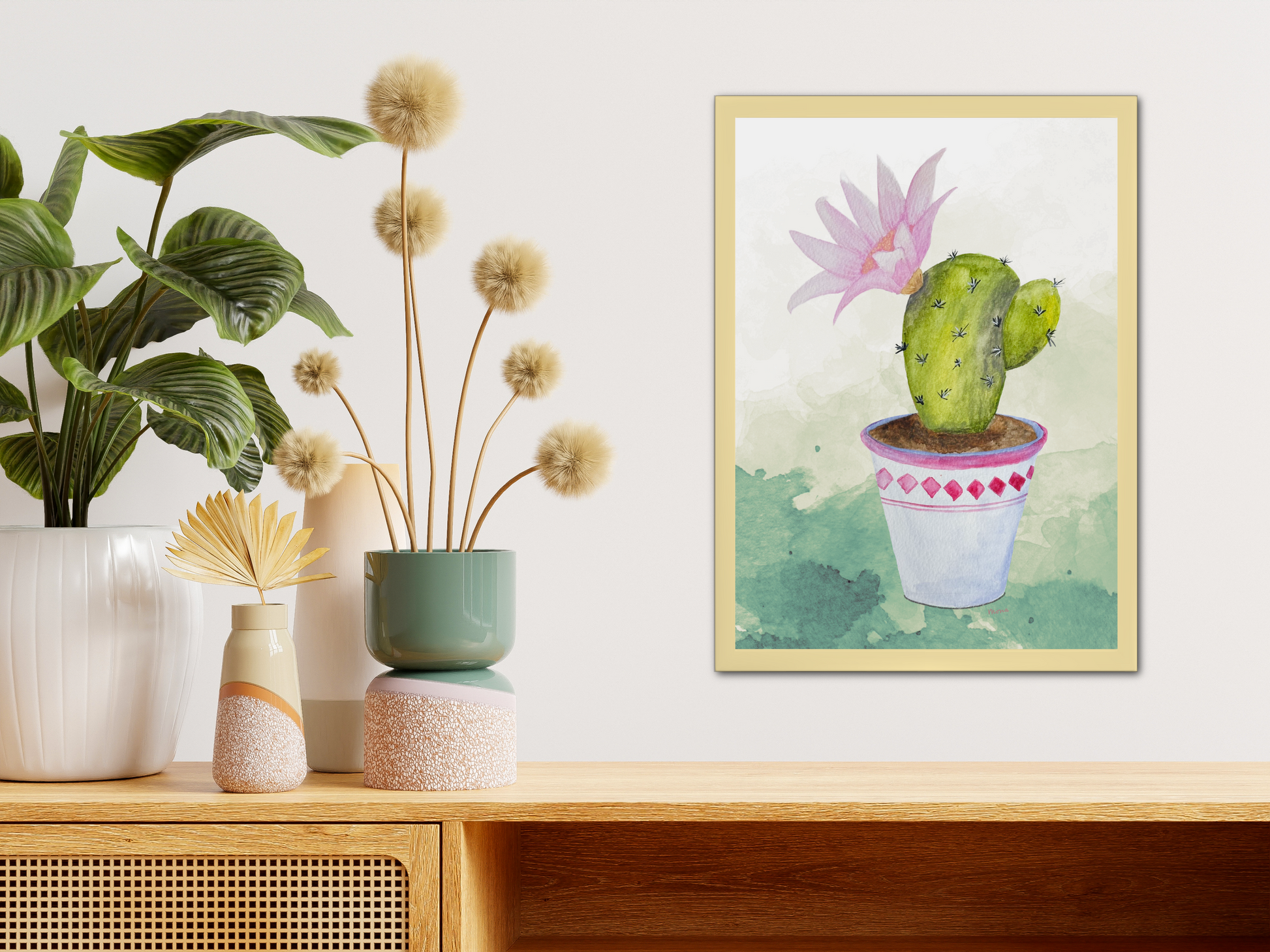 Framed artwork of a cactus with pink flower on a wooden shelf with plants.