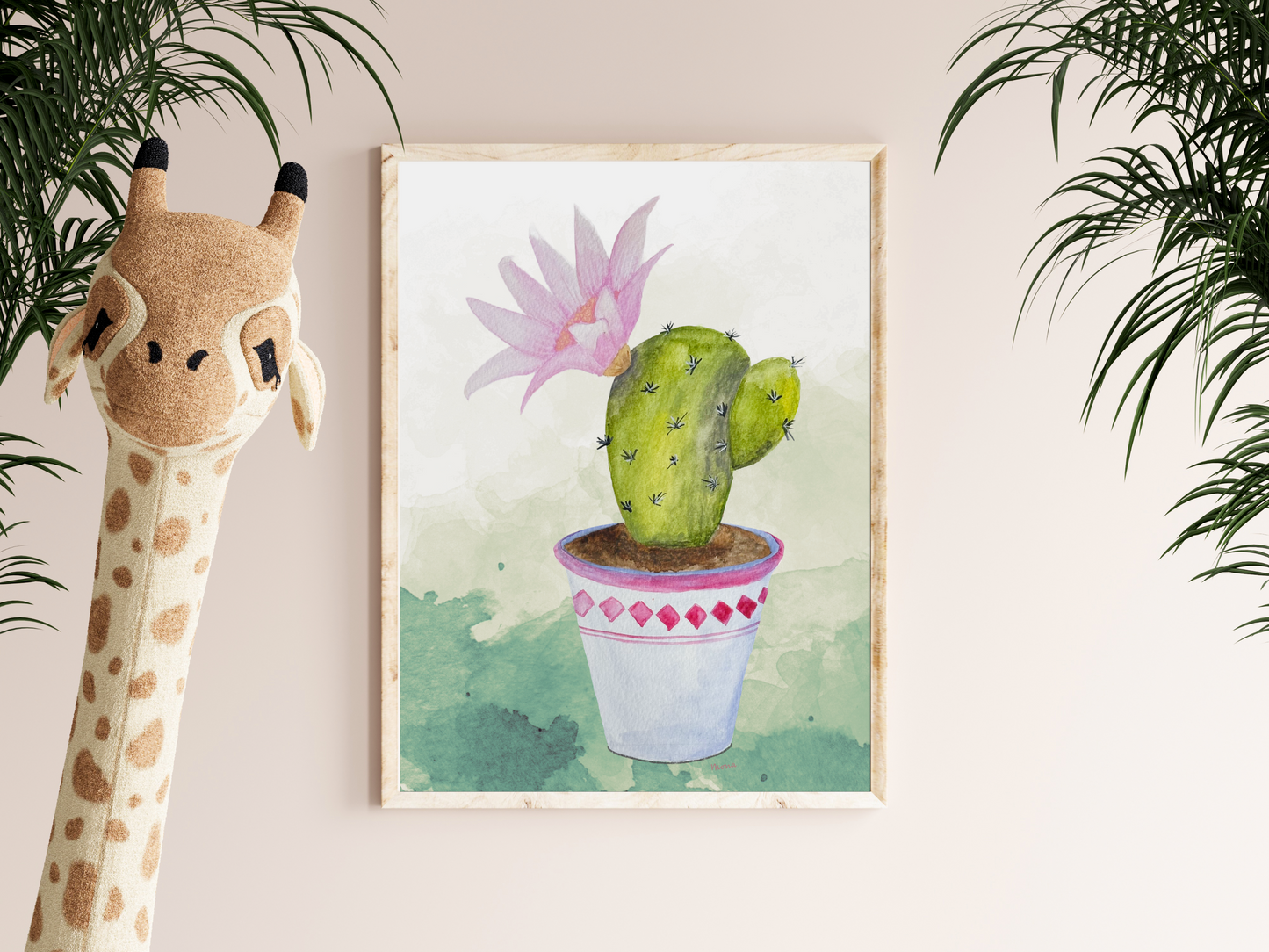 Framed artwork of a cactus with a pink flower on a wall next to a giraffe plush toy.