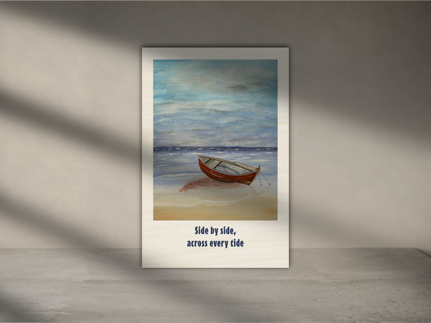A framed art print featuring a small wooden rowboat on a sandy beach under a cloudy blue sky, with the text 'Side by side, across every tide' below the artwork, displayed against a gray wall with soft window-light shadows.