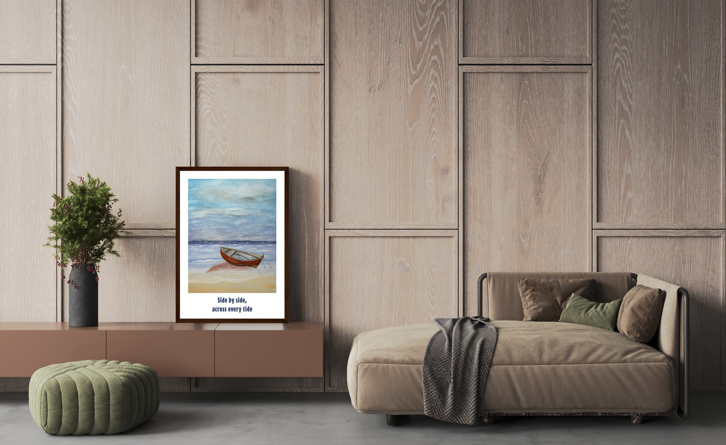 A framed art print featuring a small wooden boat on a beach with Vietnamese text below, styled in a modern living room setting next to a beige chaise lounge and a green ottoman.