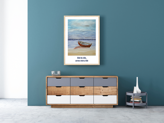 A framed art print depicting a small wooden boat on a beach with the text 'Side by side, across every tide' displayed on a teal wall above a modern wooden and gray storage cabinet.