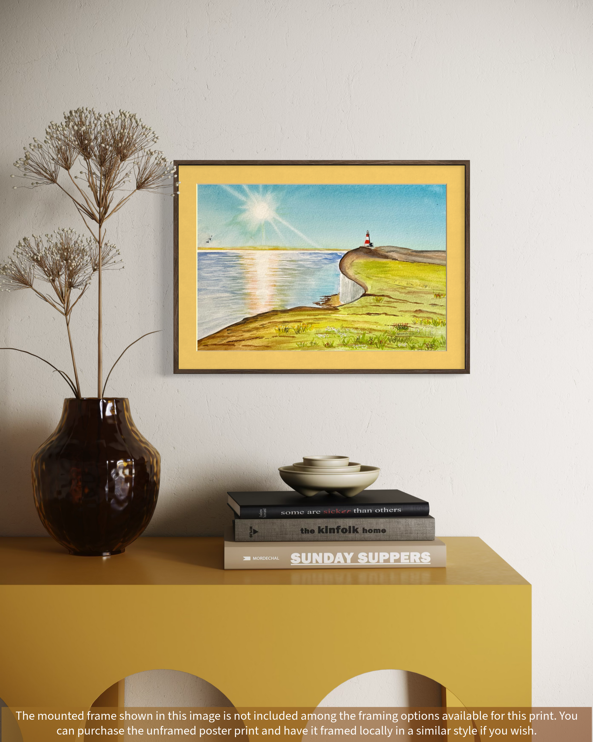 Framed artwork of a landscape with a person on a hill, placed on a yellow surface with decorative items.