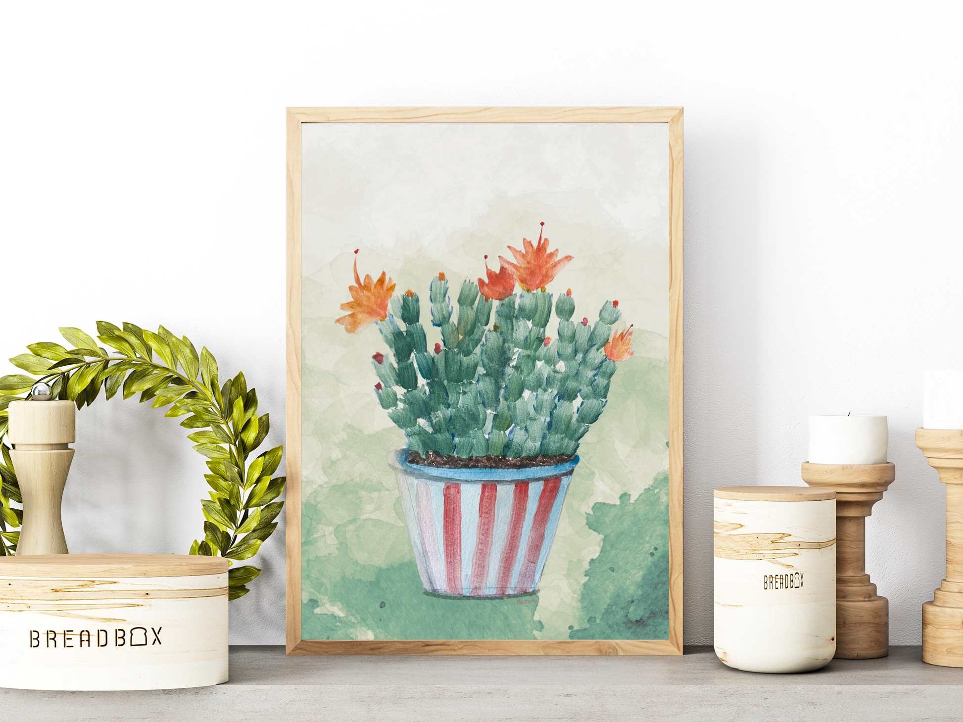 Framed artwork of a potted Christmas cactus with orange blooms, on a shelf with decorative items.